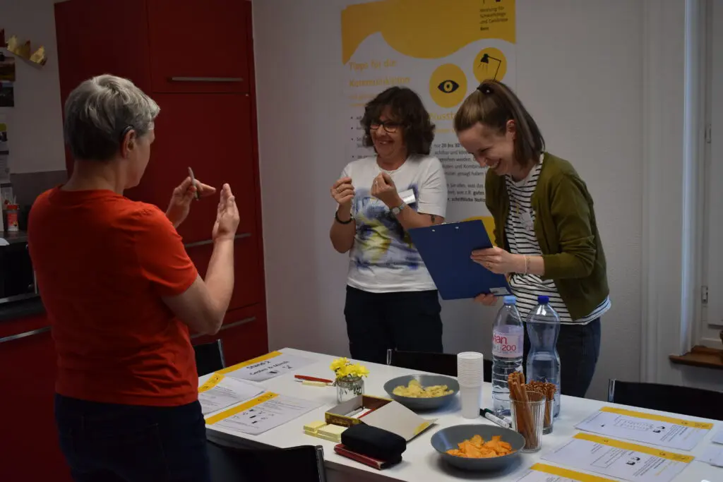Open House & Sommerfest BFSUG Bern. 3 Personen machen eine Übung zum Thema Mimik und Gestik.