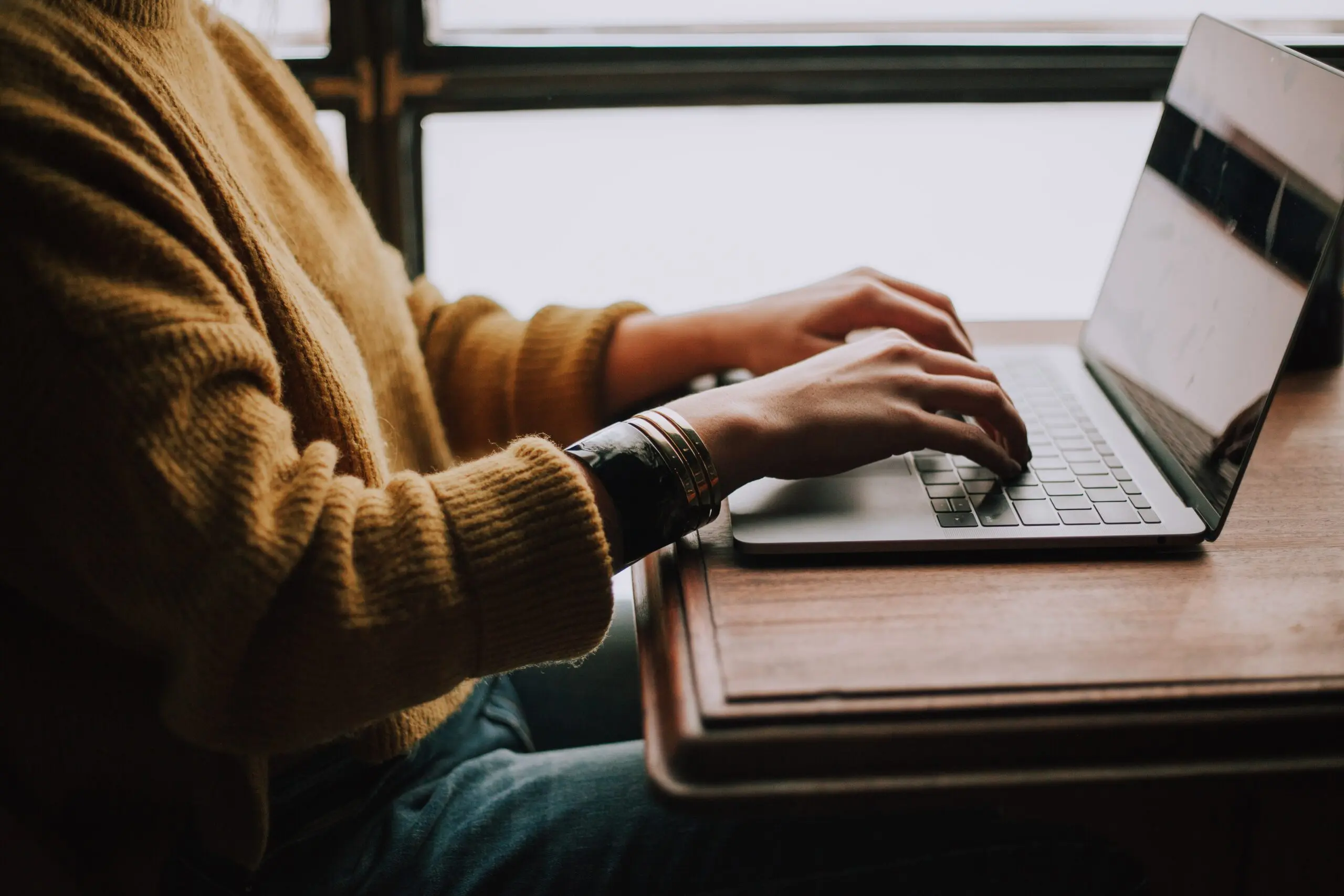 Hände, die auf Laptop tippen.
